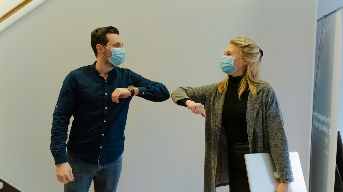 Two people greeting with facemask because of COVID 19.