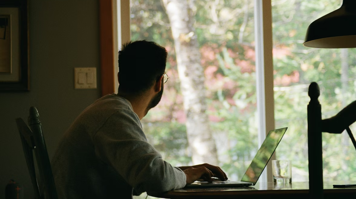Man working on laptop by window while lockdown.