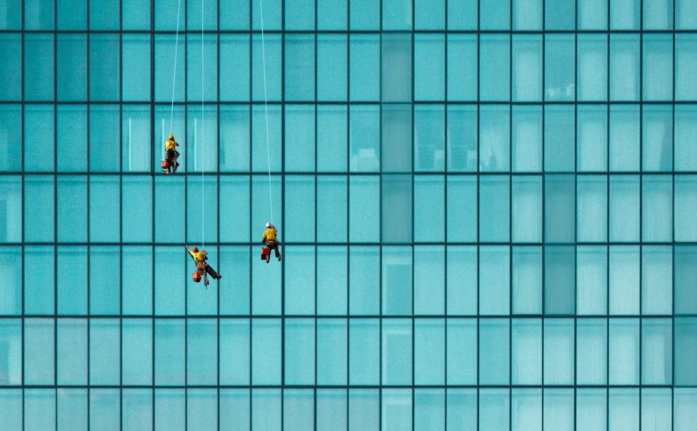 window cleaners suspended by blue building
